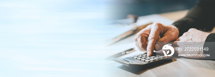 Male hand using a calculator; panoramic banner