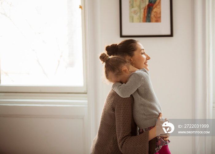 Side view of mother embracing daughter at home