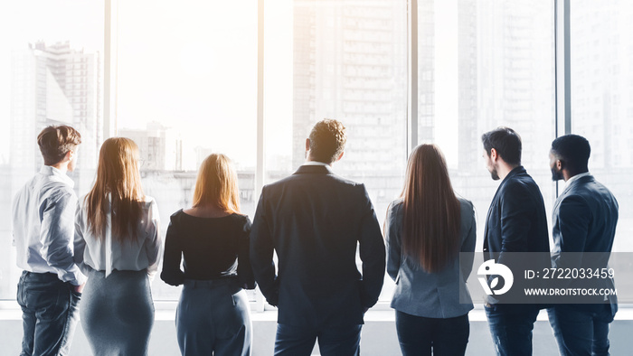 Business team looking through window, back view