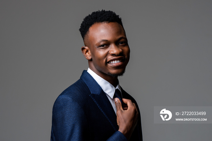 Young smiling cheerful handsome African man wearing formal business suit in studio gray isolated bac