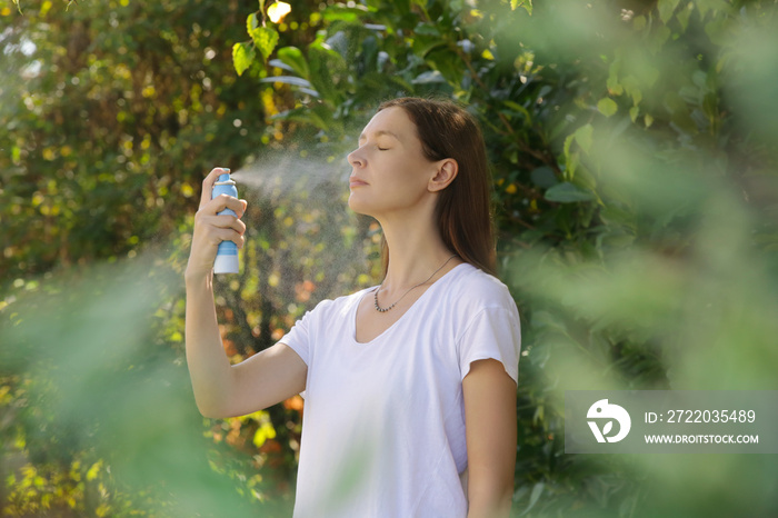 Woman spraying facial mist on her face, summertime skincare concept