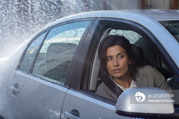 Businesswoman peering out car window in rain