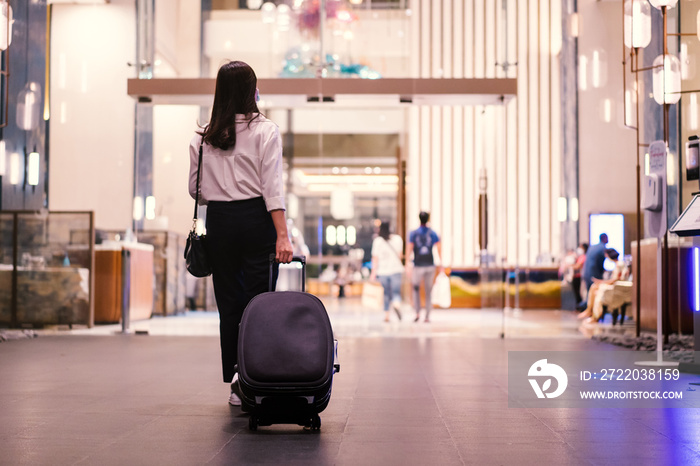 Asian young businesswoman walking and looking at the smartphone in hotel, woman in smart business ca