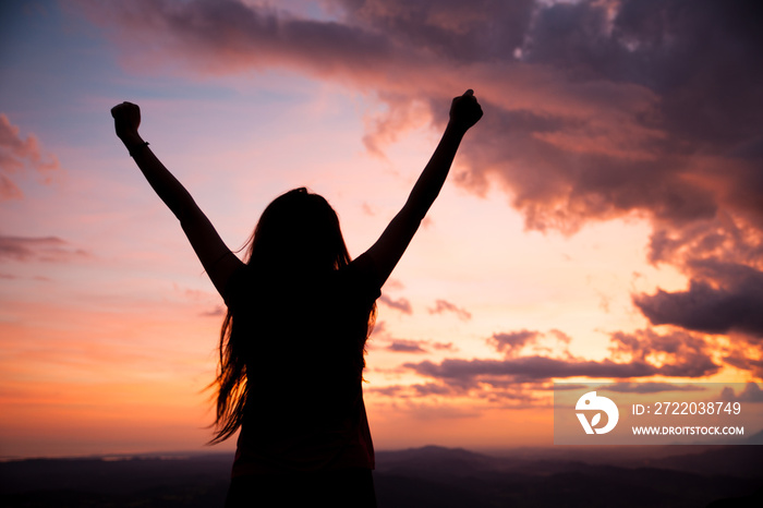 woman gesturing success - silhouette over evening sky