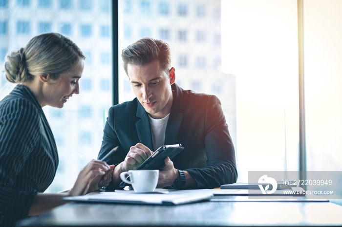 Two business people discussing work together. Businessman showing information on tablet device to hi