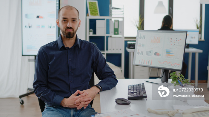 Portrait of businessman sitting at desk with computer, planning marketing strategy for development i