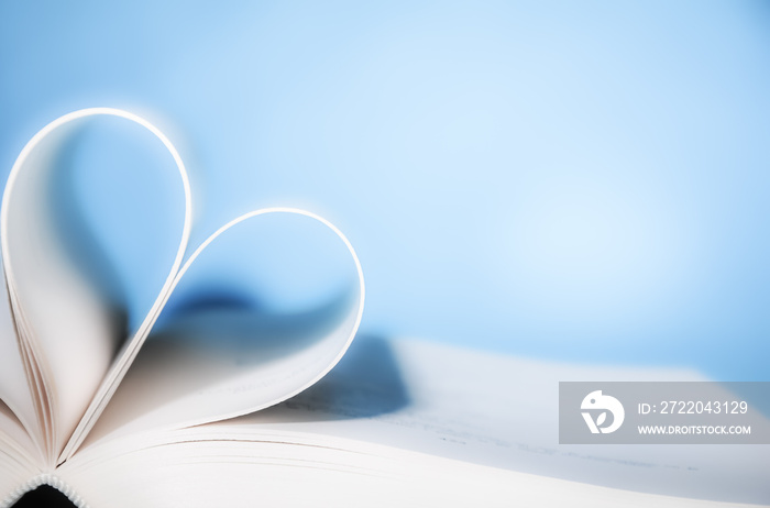 一本书的书页在蓝色背景前弯曲成一颗心