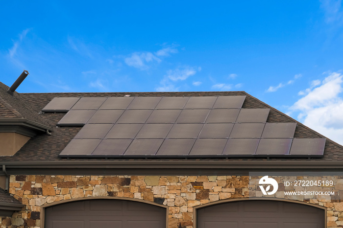 House with solar panels on the roof against blue sky with clouds