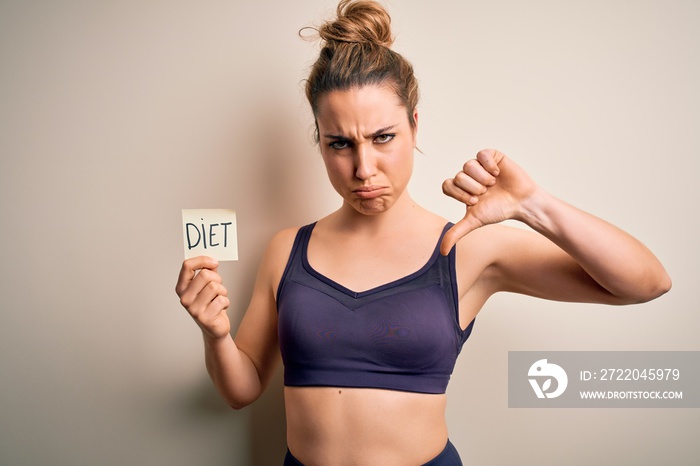 Young beautiful blonde sportswoman wearing sportswear holding reminder with diet message with angry 