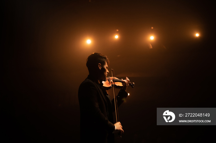 WIDE young aspiring musician playing violin on a stage of a large venue. Shot with 2x anamorphic len