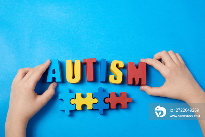 Autistic kid hands holding puzzle jigsaw and word autism, mental health concept. Autism spectrum, di