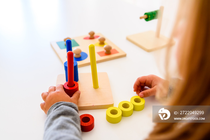 Girl in a school developing her motor skills in the hands using a colored wood material.