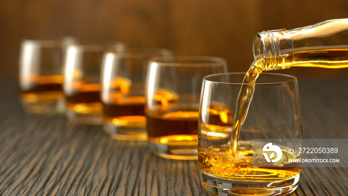 Pouring whiskey into the glass on a wooden table