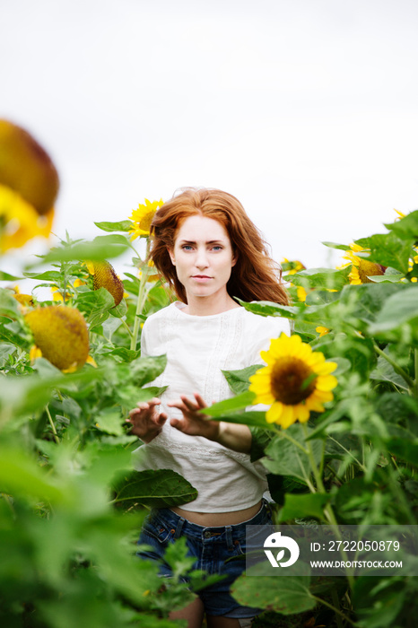 Portrait of woman standing in sunflower field against clear sky