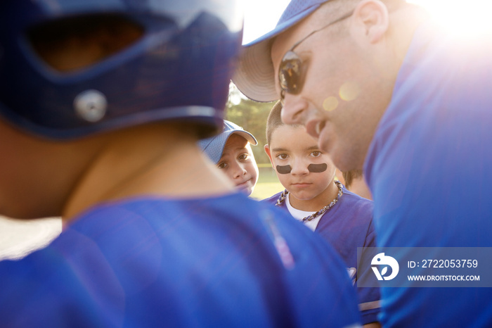 Coach talking with baseball players in field