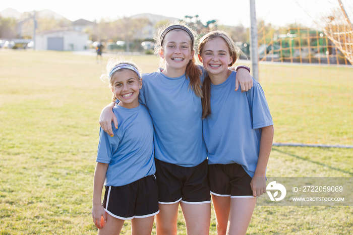 Portrait of smiling girls standing on soccer field