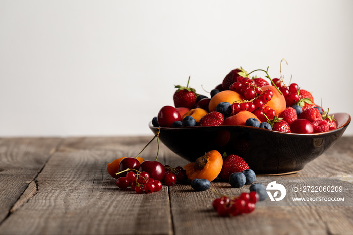 plate with fresh mixed delicious berries on wooden table isolated on white