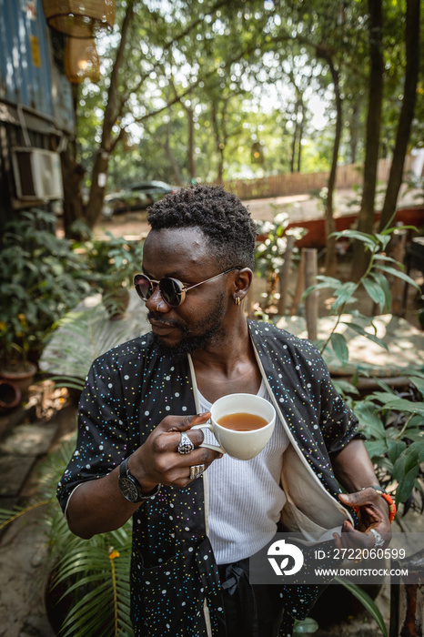 穿着和服的黑人男子在花园里拿着茶杯摆出姿势拍照