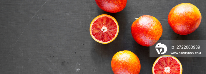 Fresh blood oranges on a black surface, top view. Flat lay, overhead, from above. Copy space.