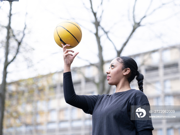 Teenage girl spinning basketball on finger