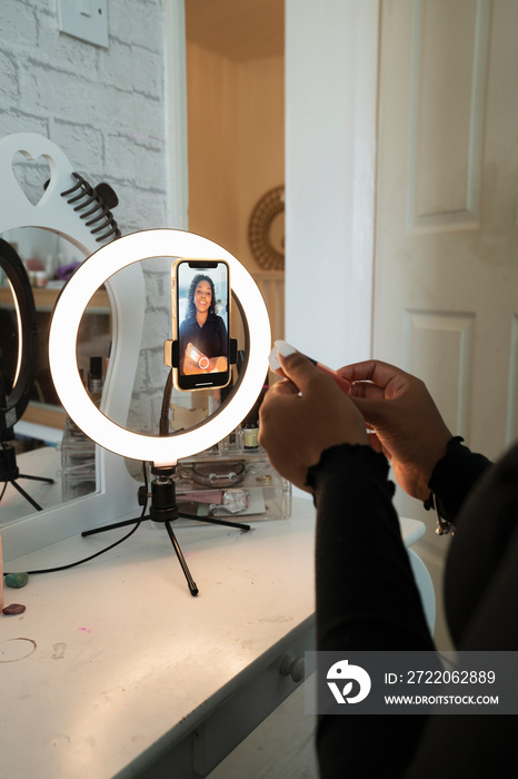 Teenage girl filming makeup video at home