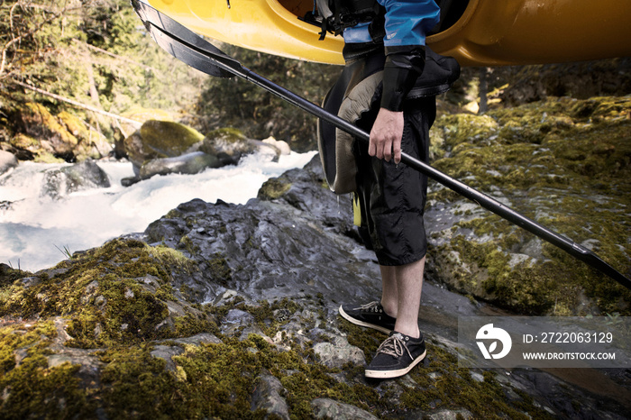 Young man holding canoe and paddle