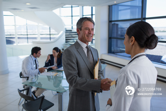 Hospital administrator shaking hands with doctor in meeting