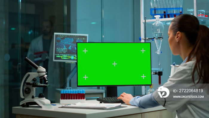 Over the shoulder shot of chemist working with green screen mock-up template on desktop computer, is