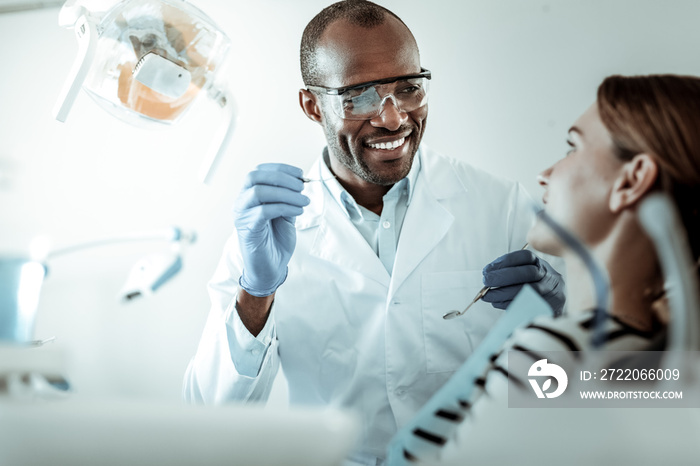 Positive African American dentist carrying special tools