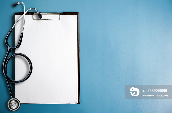 Blank medical clipboard with stethoscope on blue background. Copy space.