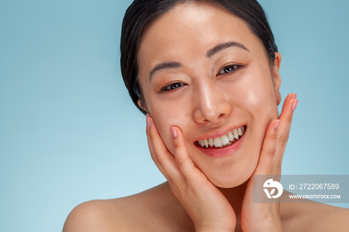 Studio portrait of smiling woman touching face