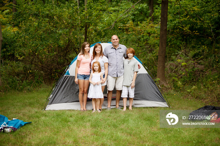 Family with three children (6-7, 12-13, 16-17) standing in front of tent