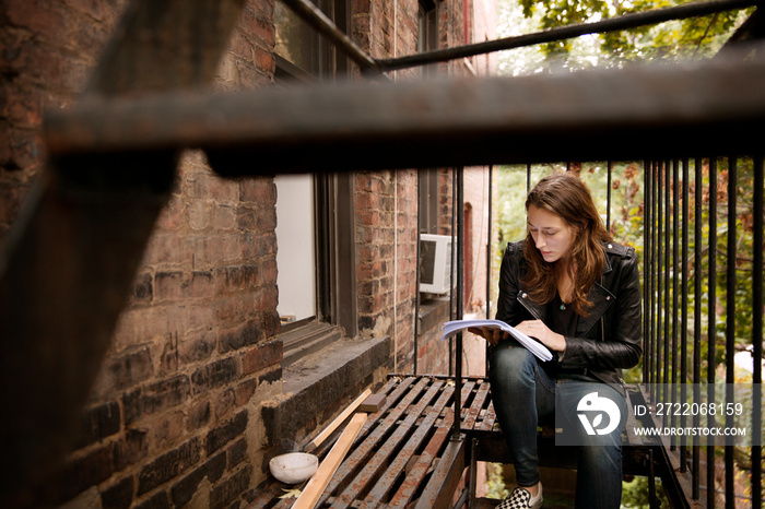 Young woman reading book on outdoor staircase