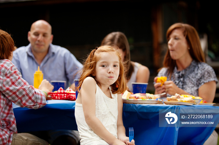 Family with three children (6-7, 12-13, 16-17) eating lunch at picnic table