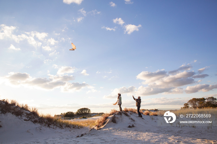 Couple playing with kite on sand dune