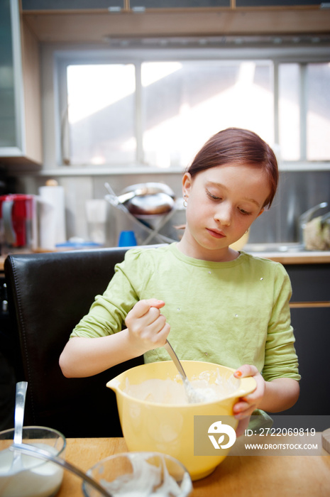 Girl (8-9) mixing ingredients in bowl