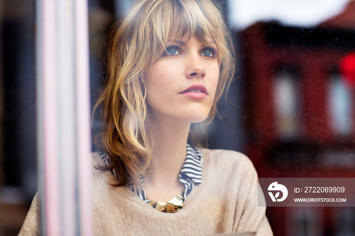 Young woman looking through window in cafe