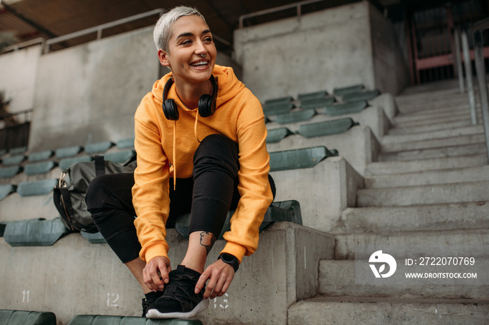 Smiling woman athlete tying shoe lace