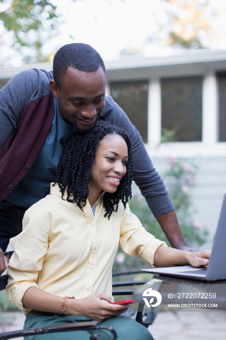 Young couple using laptop on patio