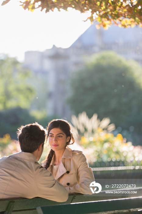 Couple talking on sunny park bench