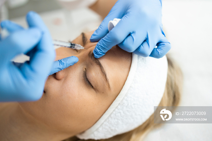 Beautician makes botox injections in the area between the eyebrows. Anti aging procedure