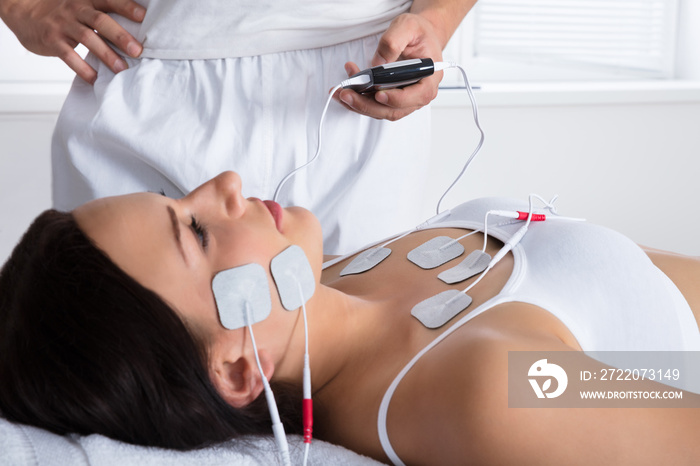 Therapist Giving Electrodes Therapy On Womans Chest And Face