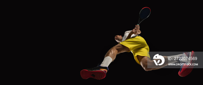 Young caucasian tennis player in action, motion isolated on black background, look from the bottom. 