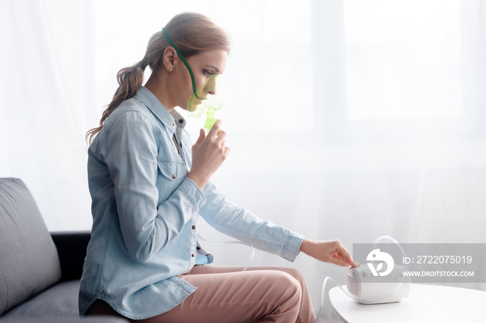 side view of woman in respiratory mask touching compressor inhaler