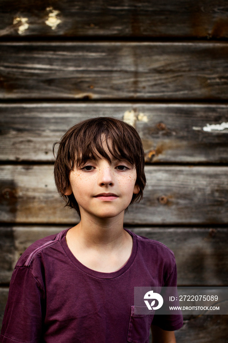 Portrait of boy against wooden wall