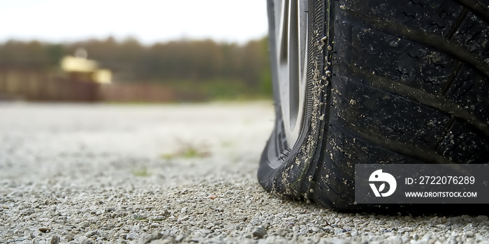 Close-up of Flat rear tire on car. The right rear broken weel. Damaged rear wheels on parking place.