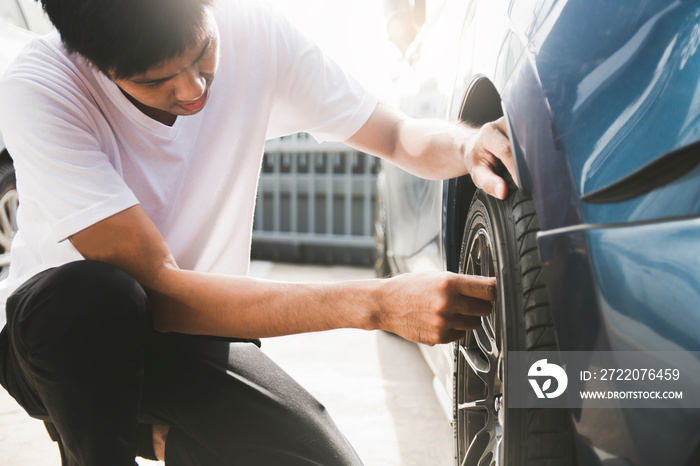 亚洲男子汽车检查测量数量充气橡胶轮胎汽车。特写手持机In
