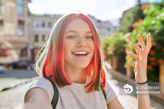 Fashionable teenage girl looks at webcam and talks on city street