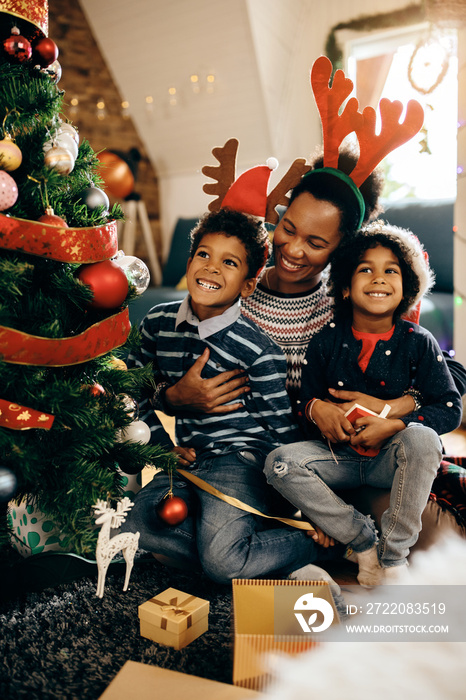 Happy African American mother with kids enjoying in Christmas day at home.