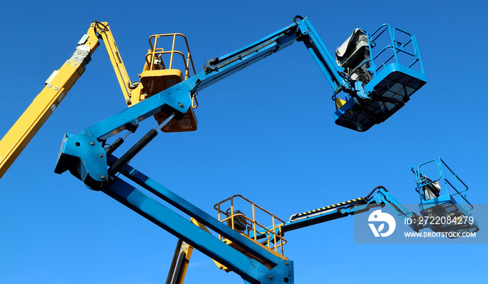 Aerial working platforms of cherry picker against blue sky